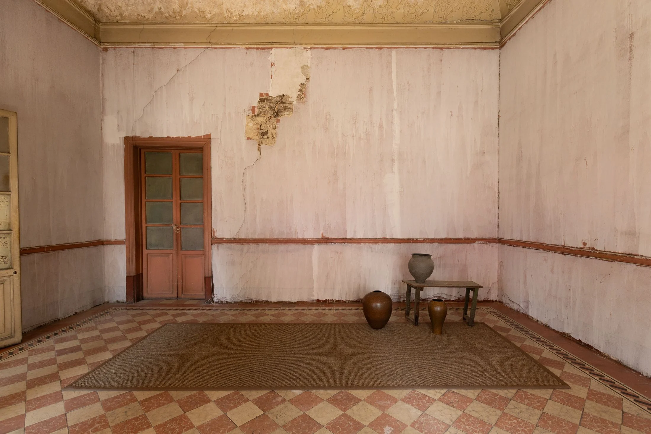 Tapete de fibra natural Formma sobre piso de mosaico en salón de muros rosados