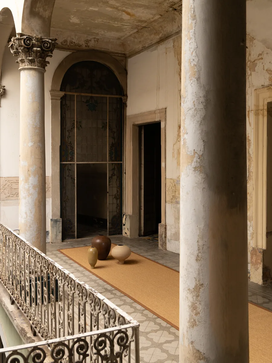 Tapete Formma de sisal en corredor de columnas con vasijas de barro